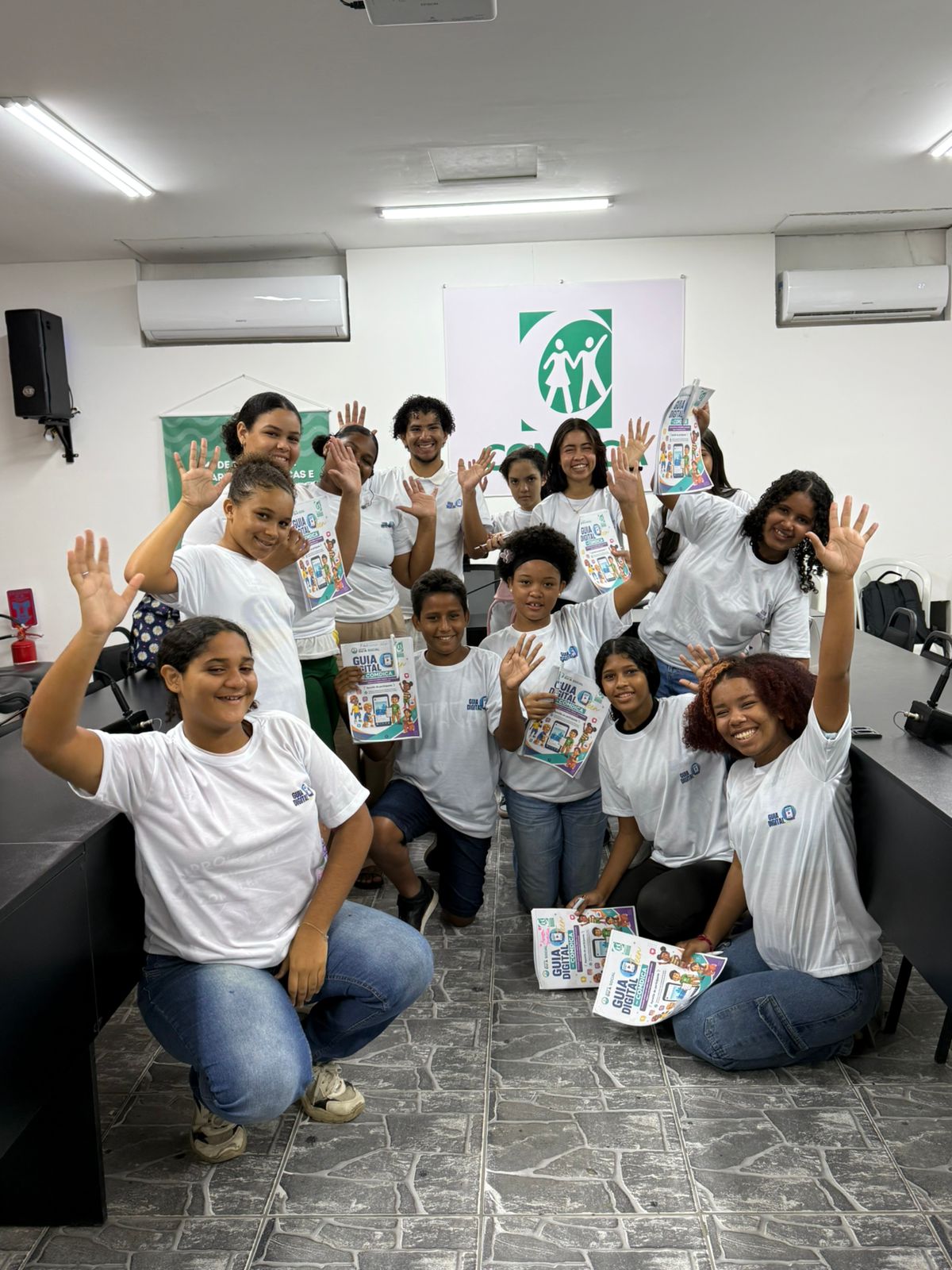 Grupo de jovens reunido em uma sala, usando camisetas e segurando materiais do Guia Digital Teen.